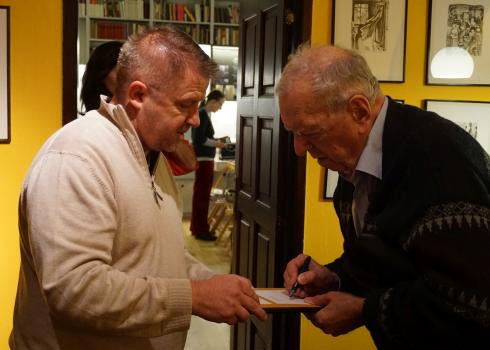 Milan Uhde (rechts) signiert sein Buch. Foto: Konstantin Kountouroyanis