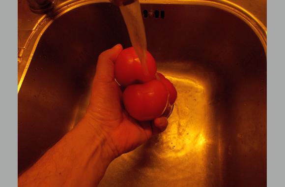 Waschen Sie die Tomaten mit kaltem Wassern und vierteln Sie sie. Geben Sie sie anschließend in die Salatschüssel.